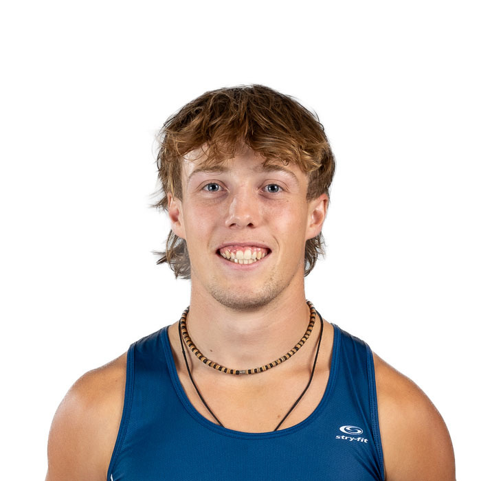 Jeune homme souriant, portant un débardeur bleu et un collier, dégageant une énergie positive et sportive.