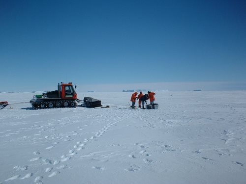 Étude polaire avec tracteur et équipe de recherche en combinaison sur la glace.