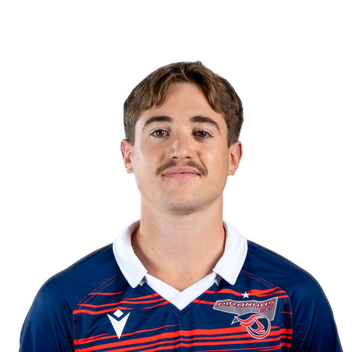 Homme en polo rayé souriant, arborant une moustache et regardant l'objectif.