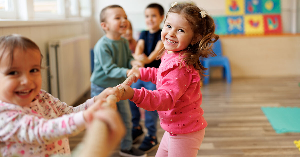 Des enfants s'amusent en tirant sur une corde, sourires aux lèvres, dans un environnement ludique et amusant.