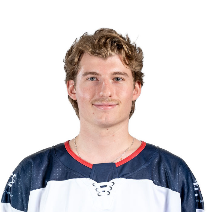 Jeune homme souriant portant un maillot de hockey, avec des cheveux bouclés et une moustache. Un regard confiant et amical.
