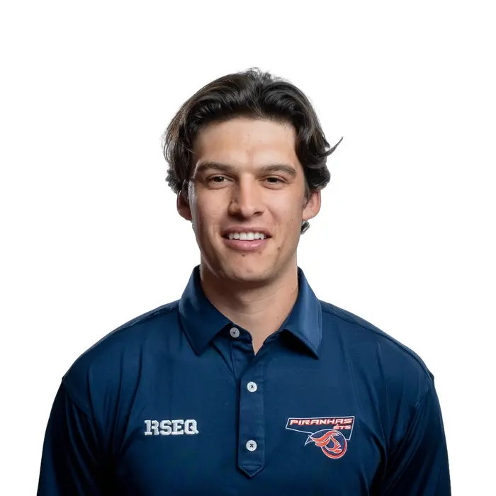 Jeune homme au look déterminé, vêtu d’une chemise bleu marine avec le logo des Piranhas, prêt à relever des défis.