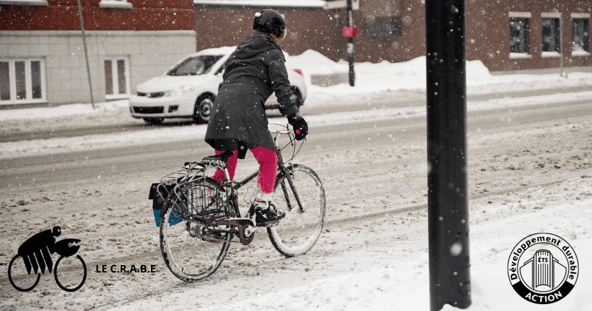 Une cycliste brave la neige sur une route urbaine, illustrant l'engagement pour un mode de transport durable.